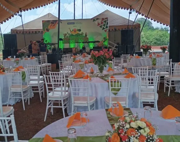 Wedding reception marquee with round tables, floral centrepieces and speakers on stands in Kenya
