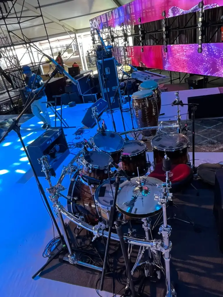 Burst finish drum kit and congas seen from stage left, with LED walls and scaffolding towers behind, in Kenya