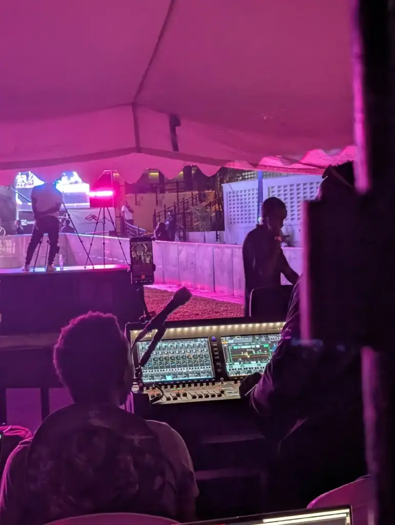 Engineers at a digital mixing console in a mix tent facing the stage during a set in Kenya