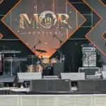 MOR Festival stage front with wedge monitors and front speakers below the backline and festival backdrop in Kenya