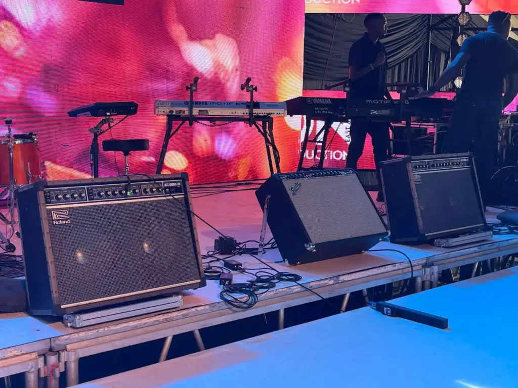Roland and Fender guitar combo amplifiers in front of keyboard stands on a stage riser in Kenya