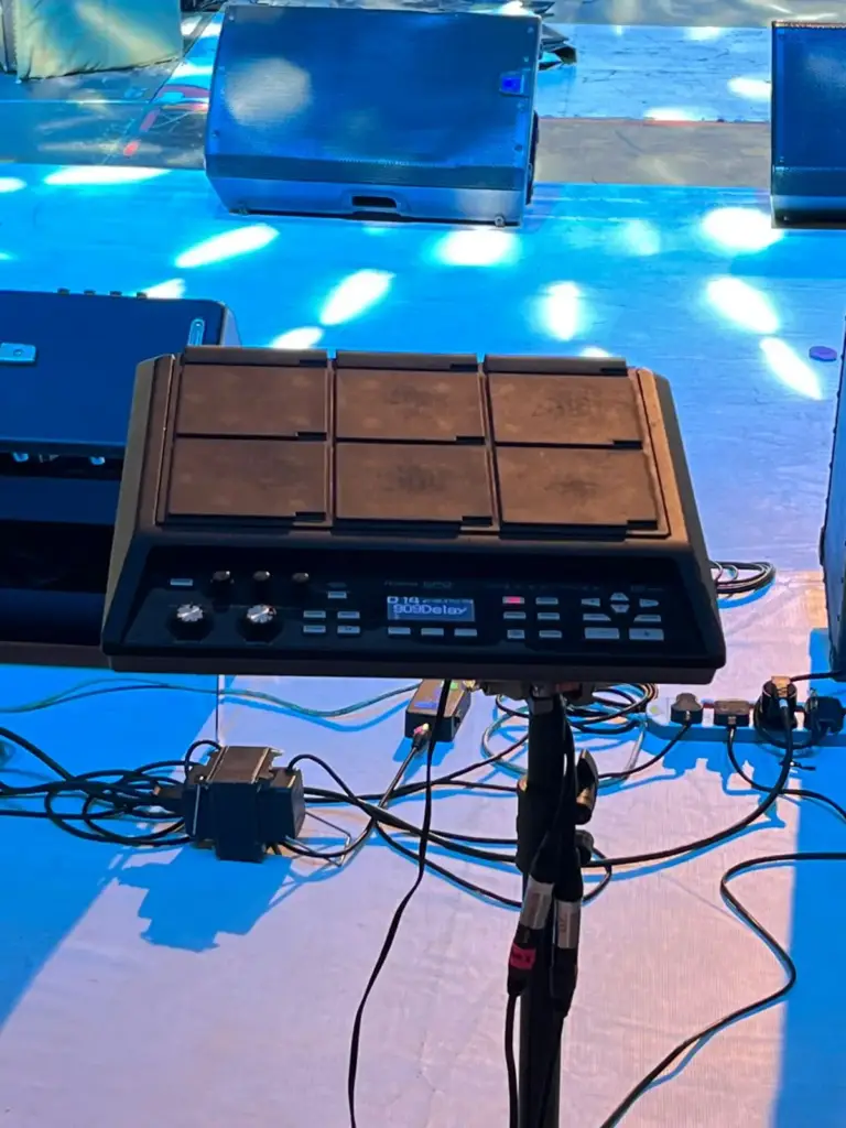Roland sampling pad mounted on a stand beside the drum riser, with stage monitors behind, in Kenya