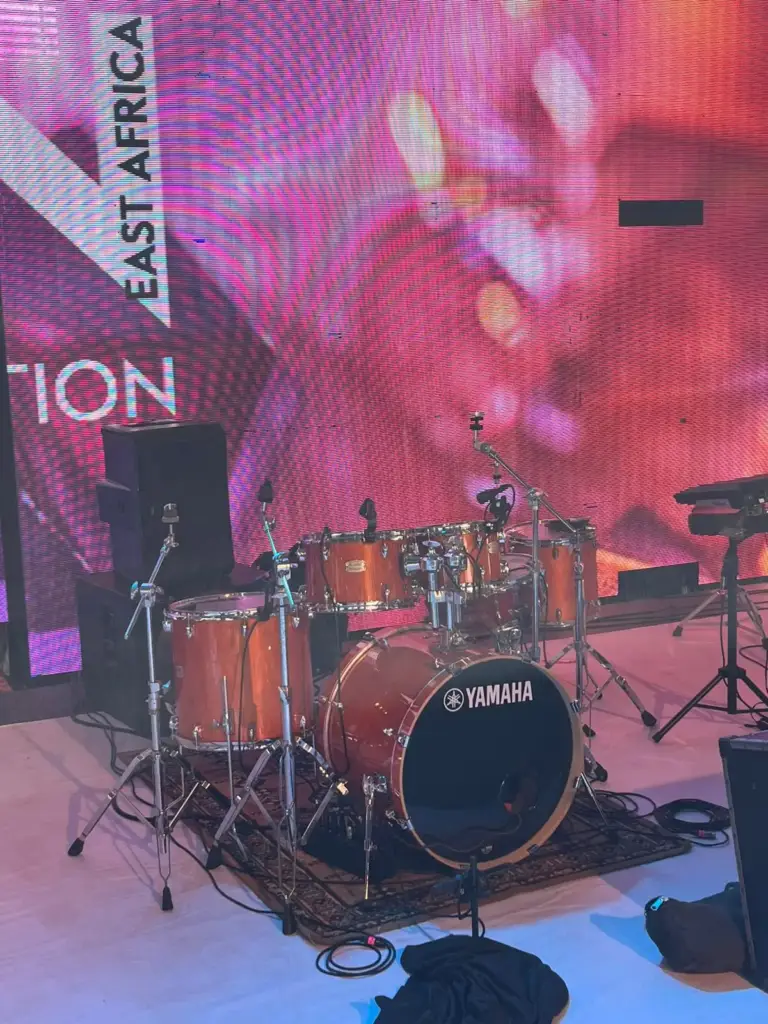 Yamaha drum kit with an amber finish set on a stage rug in front of pink LED walls in Kenya