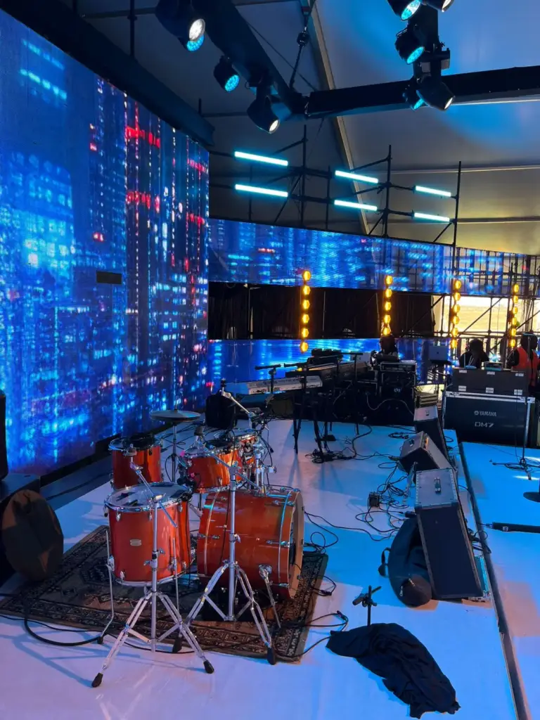 Yamaha drum kit on a stage rug with a Yamaha DM7 console case alongside and a blue LED wall behind, in Kenya