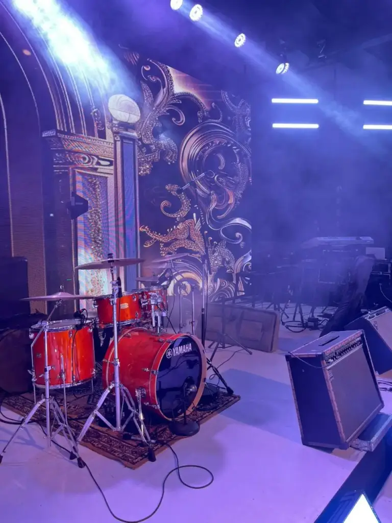 Yamaha drum kit with an orange finish set in front of an ornate silver LED backdrop under purple lighting in Kenya